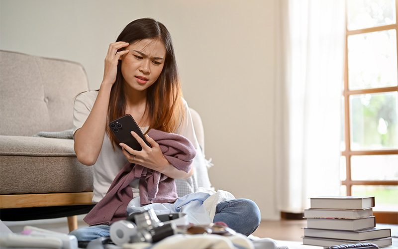 Woman stressed by cluttered small items needing a locker rental.